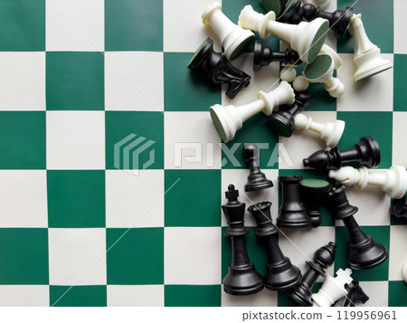 Chessboard and fallen chess pieces on green and white checkered board Chessboard and fallen chess pieces on green and white checkered board 119956961