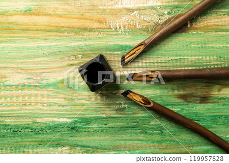 Set of calligraphy reeds covered ink with inkwell on wooden background Set of calligraphy reeds covered ink with inkwell on wooden background 119957828