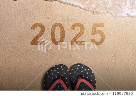 Top view of slippers and 2025 number written on beach sand background Top view of slippers and 2025 number written on beach sand background 119957980