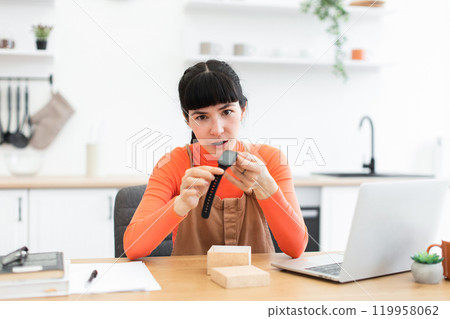 Caucasian female blogger unboxing smartwatch in modern kitchen setup 119958062