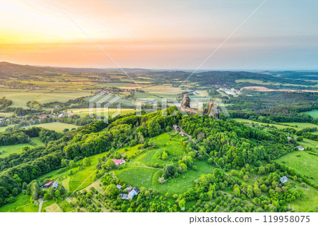Morning light illuminates Trosky castle ruins amidst the lush greenery of Bohemian Paradise, creating a breathtaking aerial perspective of this historical landmark. 119958075
