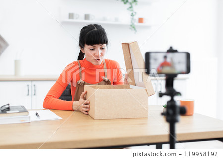 Caucasian female influencer unboxing products for online video recording 119958192