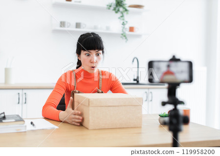 Caucasian female blogger unboxing products in home kitchen setup 119958200