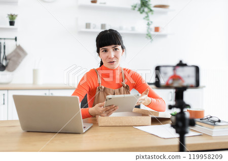 Caucasian woman unboxing digital tablet during online video session Caucasian woman unboxing digital tablet during online video session 119958209