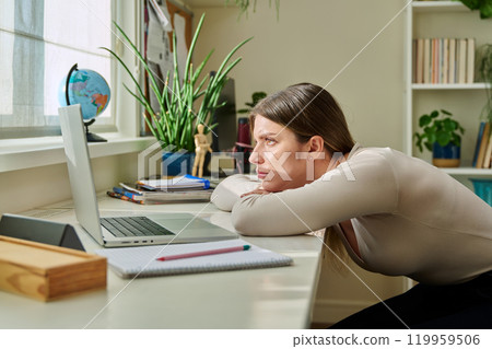 Tired sad young student woman sitting at home at desk with computer 119959506