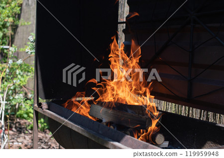 Flames rising from wood logs in a black barbecue grill outdoors Flames rising from wood logs in a black barbecue grill outdoors 119959948