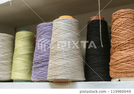 Colorful yarn spools displayed on shelf for craft and sewing projects 119960049