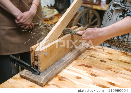 Traditional craftsmanship workshop demonstrating flax processing techniques for handmade linen production 119960094