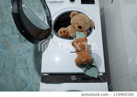 A Cute Teddy Bear is Joyfully Playing Inside a Washing Machine, Enjoying the Cozy Space 119960160