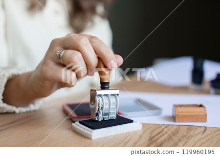 Woman Stamping Document in Office Setting 119960195