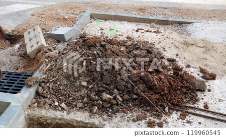 Excavated soil and debris from underground utility installation project in a city street during daytime 119960545