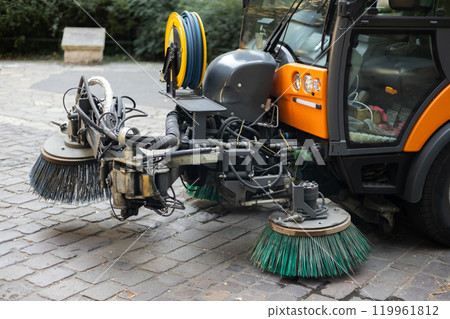 Municipal car for cleaning and brush roads or sidewalks outdoors. Steel Broom of Road Sweeper Car Machine. The concept of cleaning city streets, business, industry. 119961812