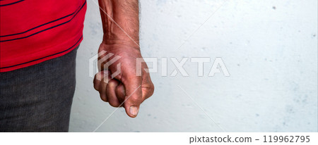 Man clenched his fist against a white wall 119962795