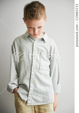 Portrait of young sad boy keeping hand in pocket. Upset kid in casual clothes posing on white background. 119963715