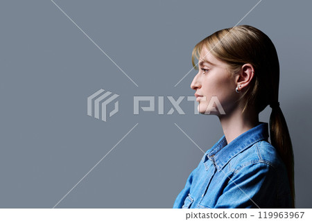 Profile view, young serious female looking forward on gray studio background 119963967