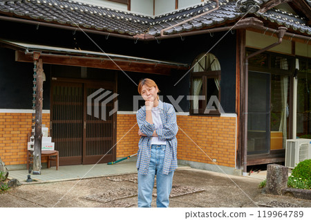 一個女人在古老的民居、空置的房子、遺產、鄉村前歪著頭 119964789