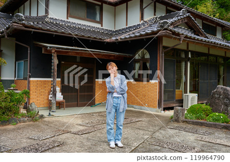 一個女人在古老的民居、空置的房子、遺產、鄉村前歪著頭 119964790