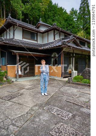 一個女人在古老的民居、空置的房子、遺產、鄉村前歪著頭 119964791