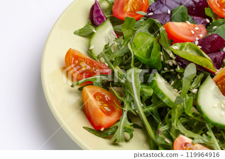 Vegetable salad of tomato, cucumber, greens with sesame on the plate. 119964916