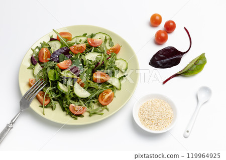 Vegetable salad of tomato, cucumber, greens on the plate with a fork. 119964925