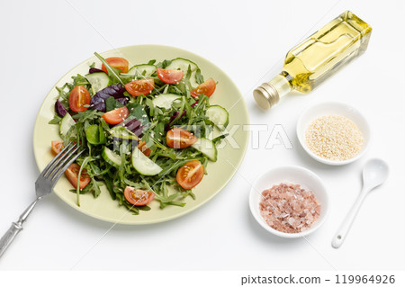 Vegetable salad of tomato, cucumber, greens on the plate with a fork. 119964926