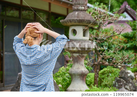 A woman holding her head in front of an old house, vacant house, countryside, inheritance A woman holding her head in front of an old house, vacant house, countryside, inheritance 119965074