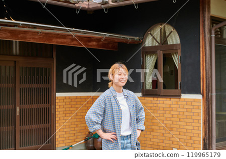 Smiling woman in front of an old house, countryside, Japanese garden 119965179