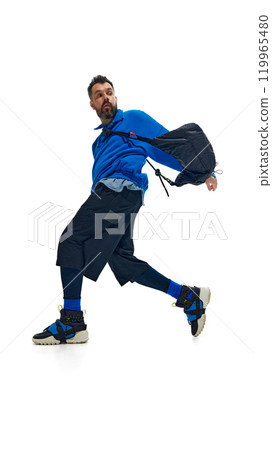 Fashion-forward man in vibrant blue outfit, captured mid-movement with dynamic twist. against white studio background. 119965480