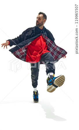 Man confidently stepping forward, wearing bold combination of red sweatshirt, plaid-lined jacket, and vibrant sneakers against white studio background. 119965507