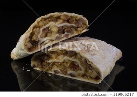 Apple strudel cut close-up on a black background; 119966217