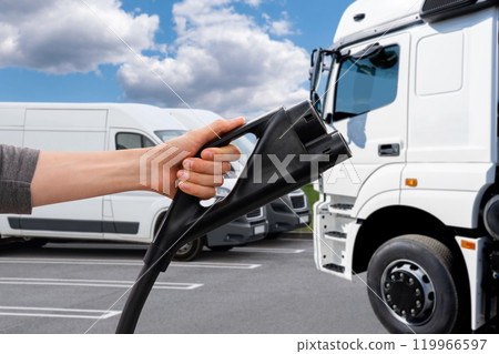 Hand with charging plug on a background of electric truck. Concept. Hand with charging plug on a background of electric truck. Concept. 119966597