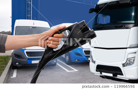 Hand with charging plug on a background of electric truck. Concept. 119966598
