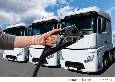 Hand with charging plug on a background of electric truck. Concept. Hand with charging plug on a background of electric truck. Concept. 119966605