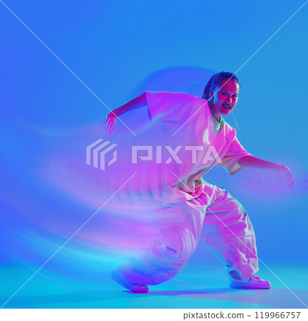 Creative design. Dynamic image of young woman in white clothes dancing hip hop with passion on blue background in neon with motion blur effect. Creative design. Dynamic image of young woman in white clothes dancing hip hop with passion on blue background in neon with motion blur effect. 119966757