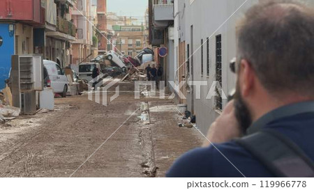 Person filming disaster aftermath on a Valencia street Person filming disaster aftermath on a Valencia street 119966778