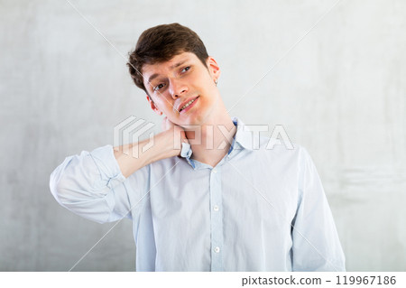 Young guy holding his sore neck Young guy holding his sore neck 119967186