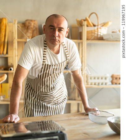 Portrait of experienced male baker in an apron in interior of private bakery Portrait of experienced male baker in an apron in interior of private bakery 119967195