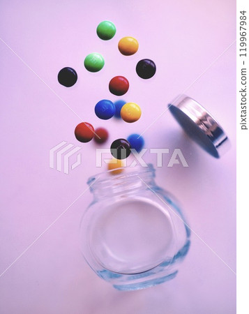 Colorful sweets popping out of a jar Colorful sweets popping out of a jar 119967984
