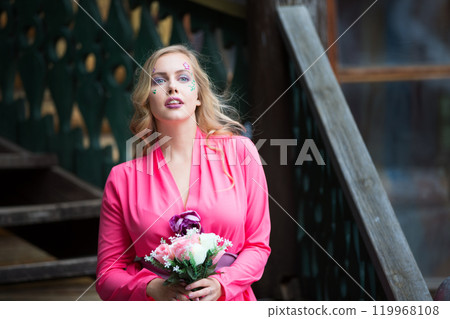 Beautiful Slavic blonde girl with long hair and creative makeup in a pink dress. Beautiful Slavic blonde girl with long hair and creative makeup in a pink dress. 119968108
