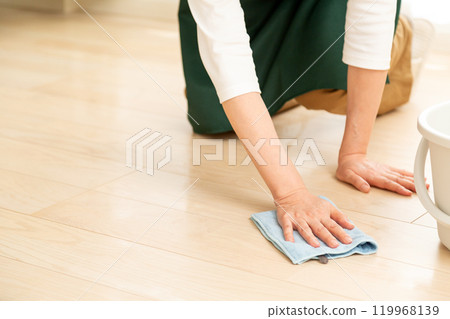 A middle-aged to senior woman wiping the floor with a damp cloth 119968139