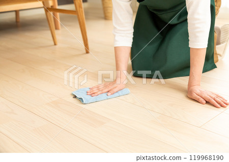 A middle-aged to senior woman wiping the floor with a damp cloth 119968190