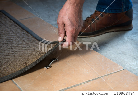 A person getting a key from under their mat 119968484