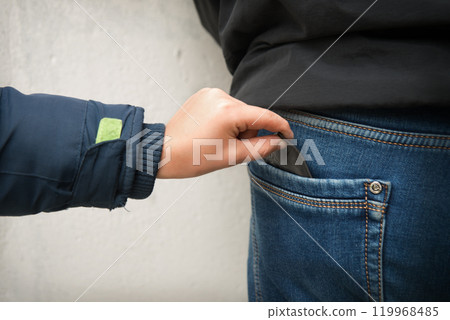 A hand stealing a wallet from a pocket 119968485