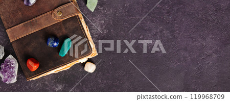Rustic Leather Journal with Healing Crystals on Dark Background banner 119968709