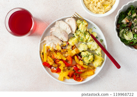Boiled potatoes, roasted vegetables, and lean chicken breast come together with a fresh salad of tomatoes and cucumbers with seeds, accompanied by a light raspberry compote 119968722