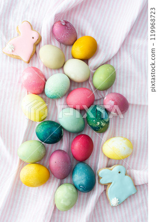 Multi-colored Easter eggs with decorative bunnies on a pink tablecloth, Happy Easter holiday 119968723
