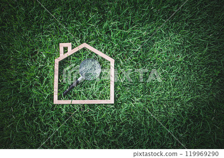 Magnifying Glass Inside Wooden House Outline on Green Grass Representing Home Inspection and Attention to Detail 119969290