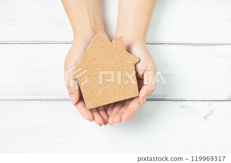 Hands of Ownership: Holding a Cork House Cutout on White Background 119969317