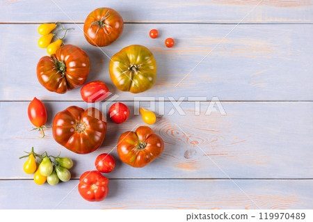 Red, green, yellow and striped tomatoes on blue wooden table. Flat lay. Healthy food, fresh healthy vegetables from the garden 119970489