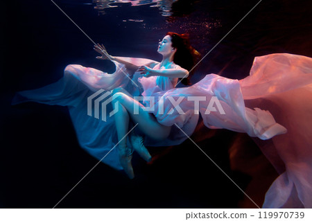 Attractive woman, model, ballerina underwater in a fluttering dress. Soft blurred focus. Attractive woman, model, ballerina underwater in a fluttering dress. Soft blurred focus. 119970739